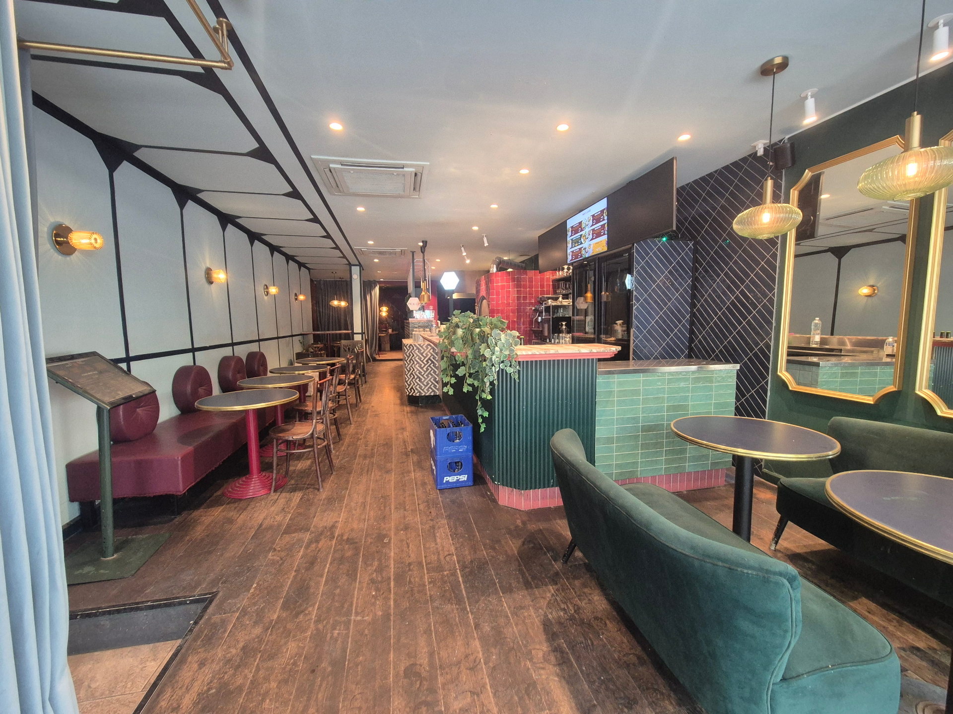 Intérieur Wrap & Go — banquettes bordeaux, comptoir vert, luminaires laiton
